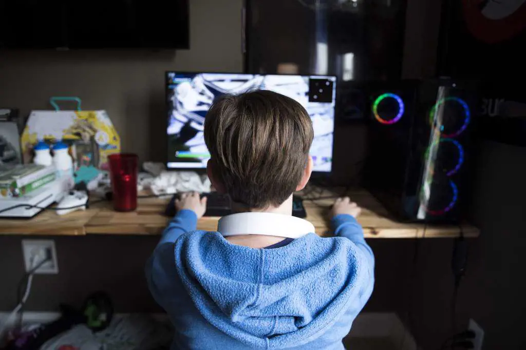 Rear View of Teen Boy Playing Gaming Computer on a Messy Desk