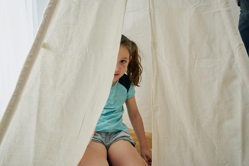 girl looking in a white teepee tent inside their house. home concept