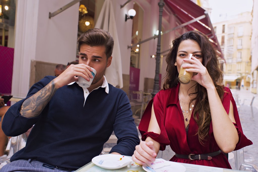 Young couple drink coffee on the terrace of a bar