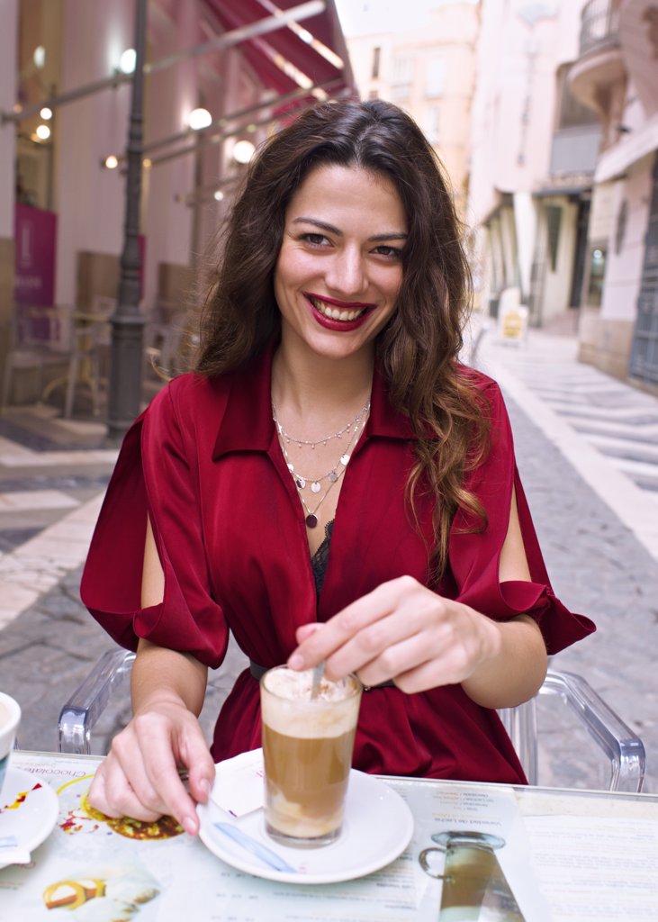Young woman drinking coffee on a terrace in the street