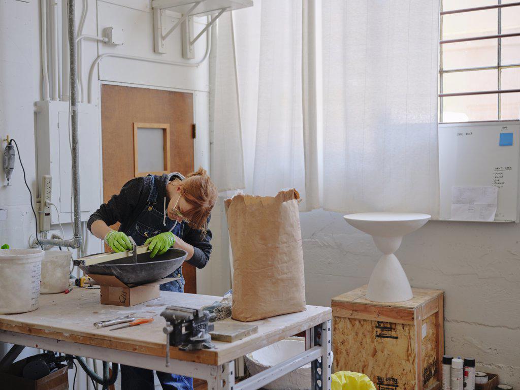 Professional female sculptor measuring her work in her studio