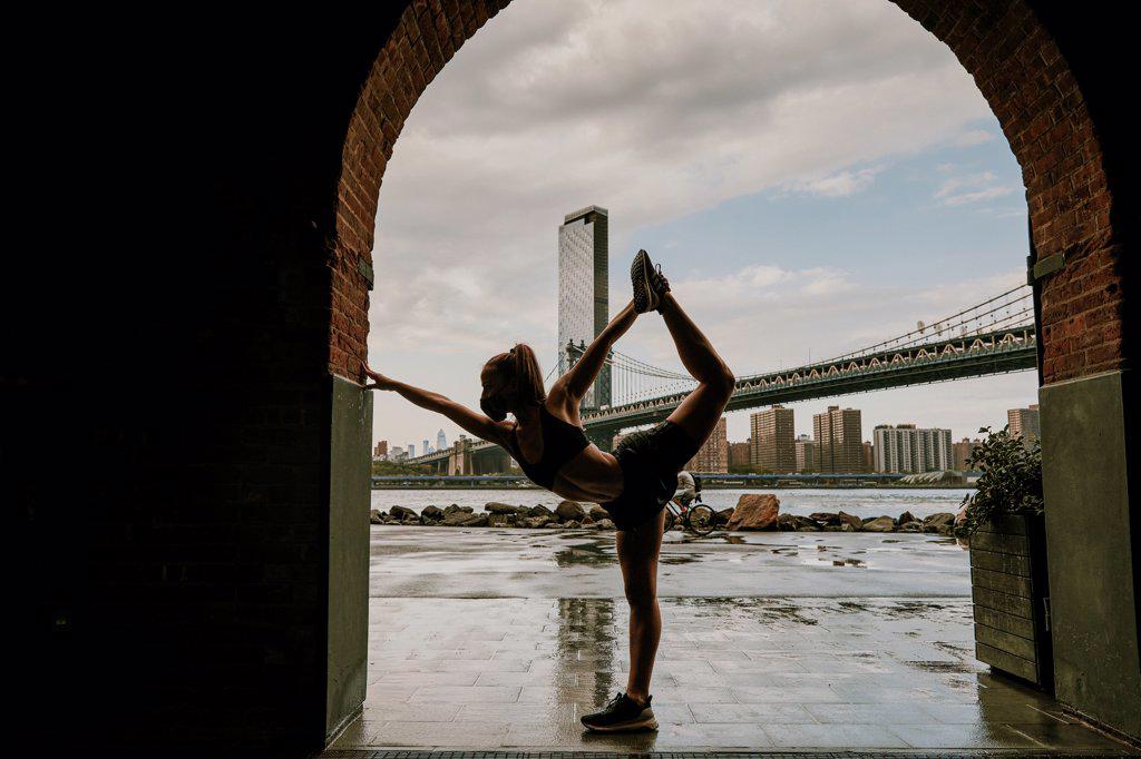 Silhouette of woman stretching against skyline.