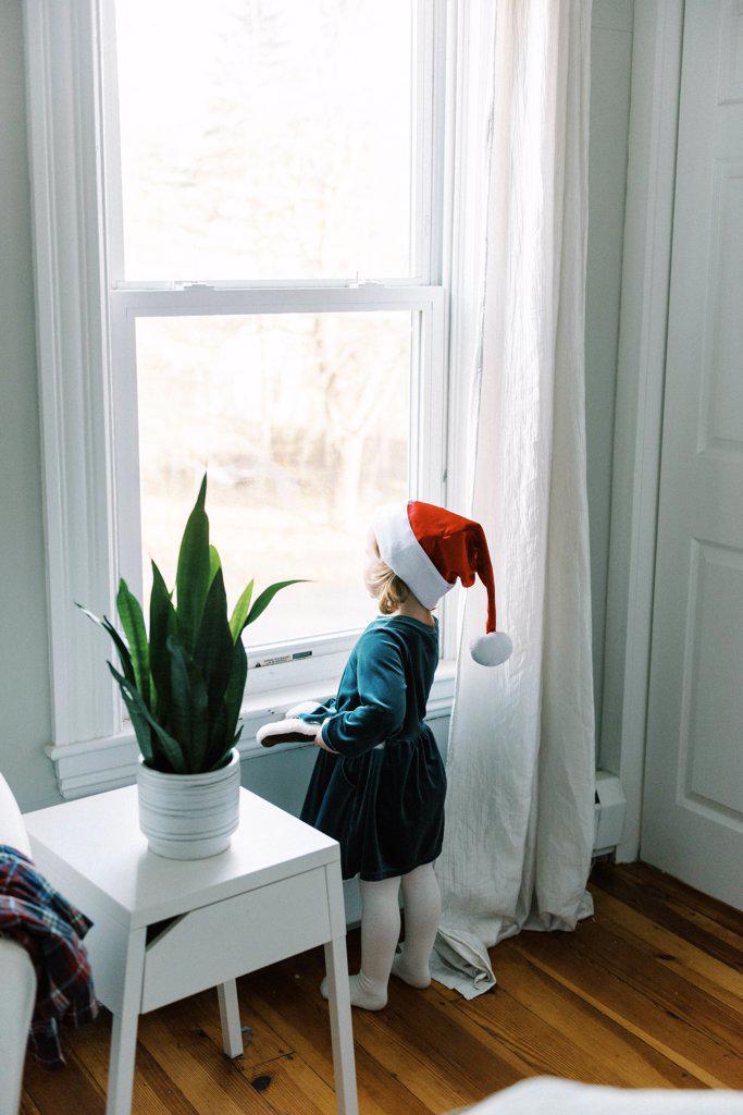 Little girl looking out window waiting for Santa clause on Christmas