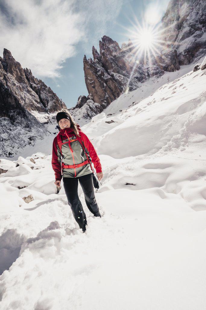 Young female hiking through snow in front of Dolomite Rock faces