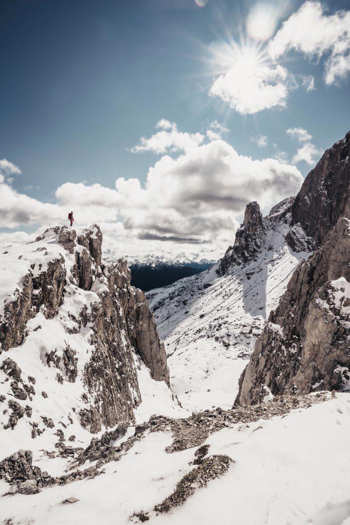 Female alpinist standing on top of snowy mountain peak enjoying view