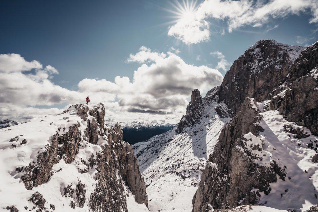 Landscape shot of female alpinist on peak against blue sky