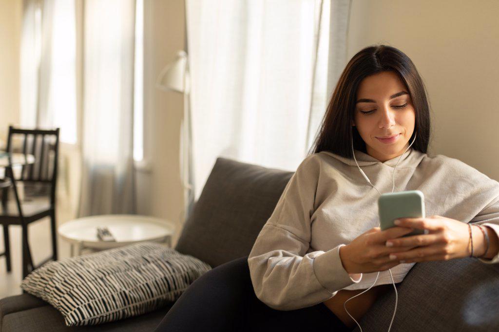 Content casual woman in earphones enjoying music at home