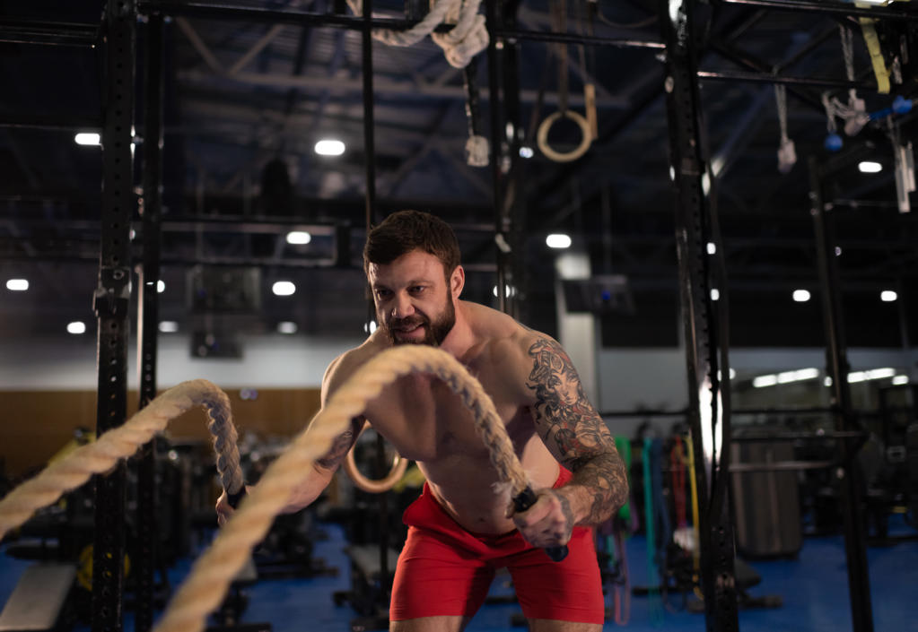 Smiling sportsman doing battling ropes exercise