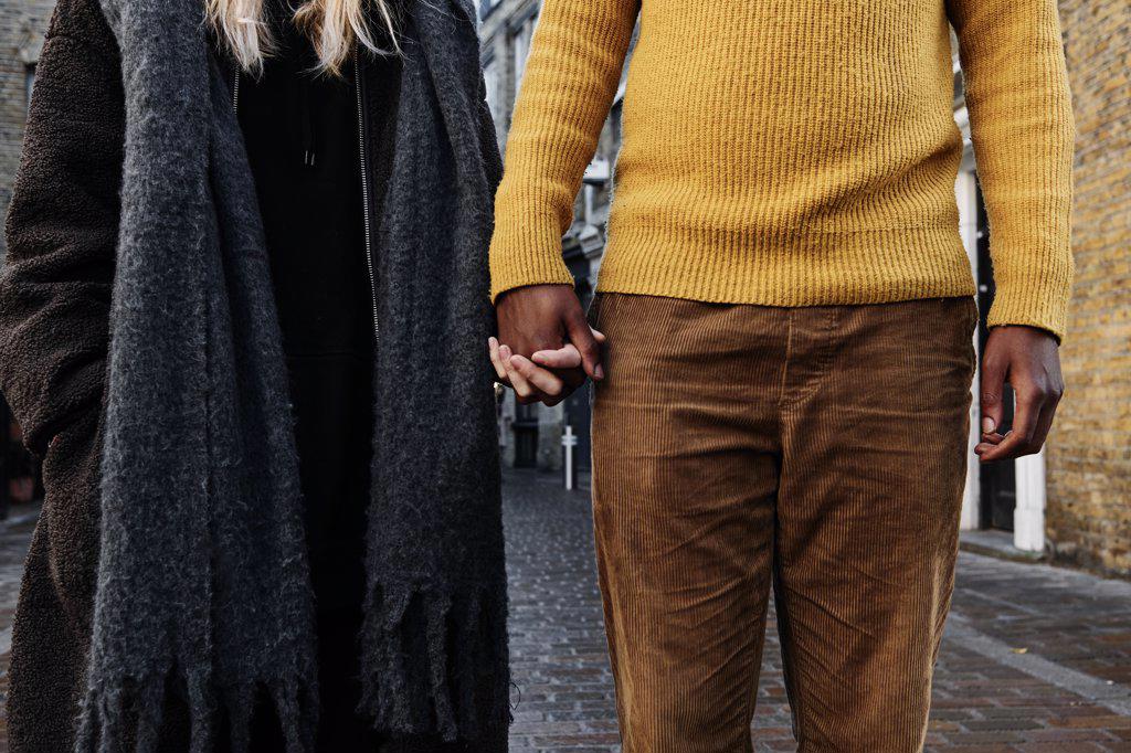 cropped view of biracial couple holding hands. unrecognizable