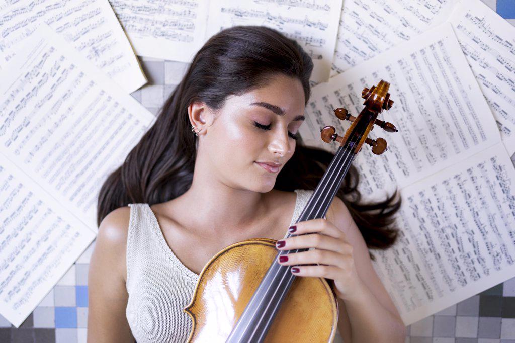 Girl lying on the floor with a viola and surrounded by musical scores.