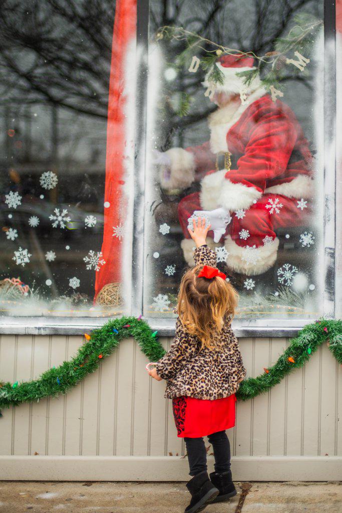 Toddler reaches for santa through window