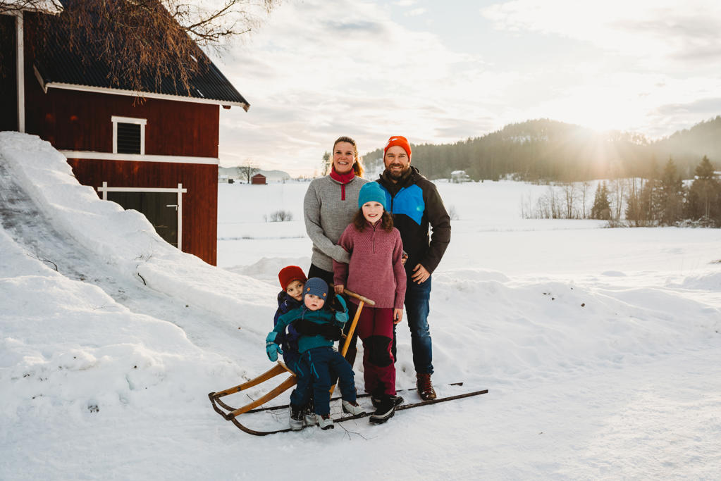 Happy smiling family in snowy countryside farm during sunset