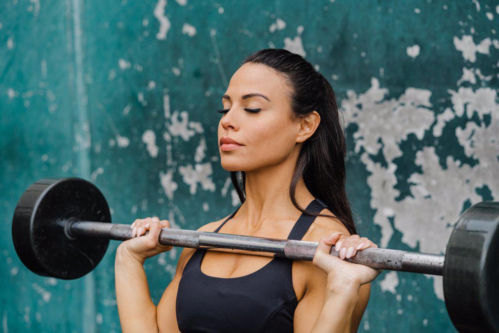 strong female weight lifting at wall of an outdoor gym