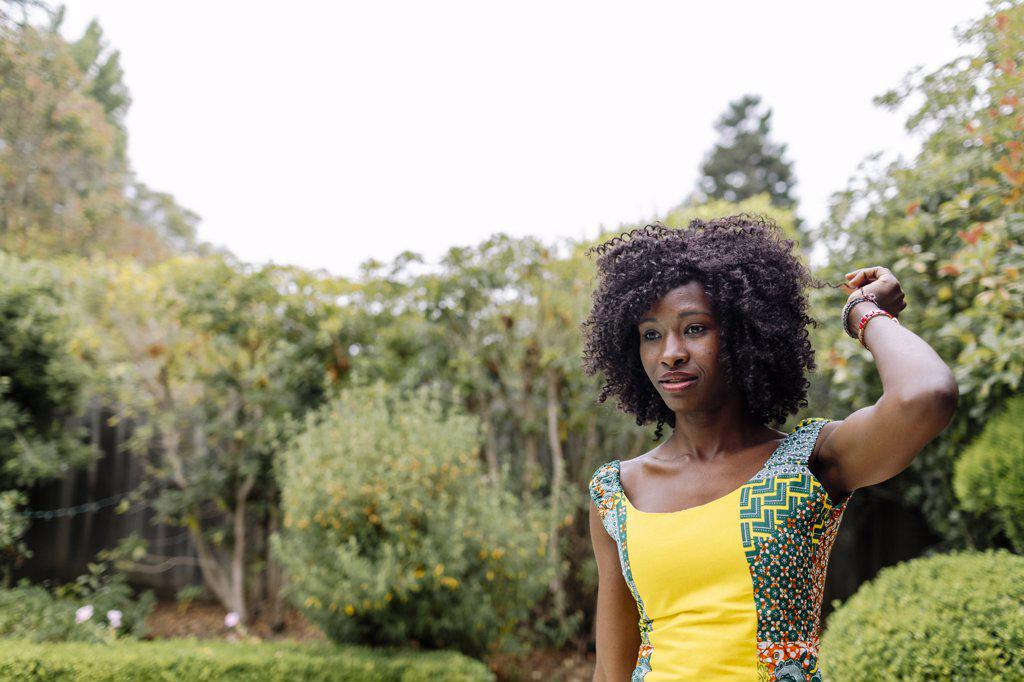 Outdoor headshoot afro hair woman looking away by garden