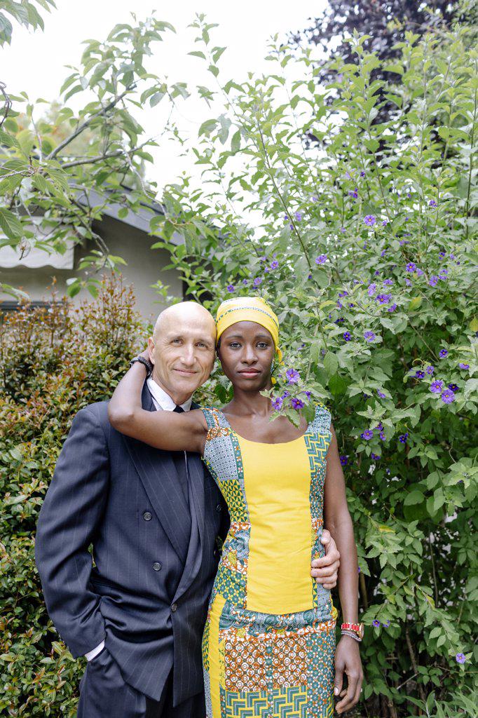 Interracial couple standing up portrait by garden
