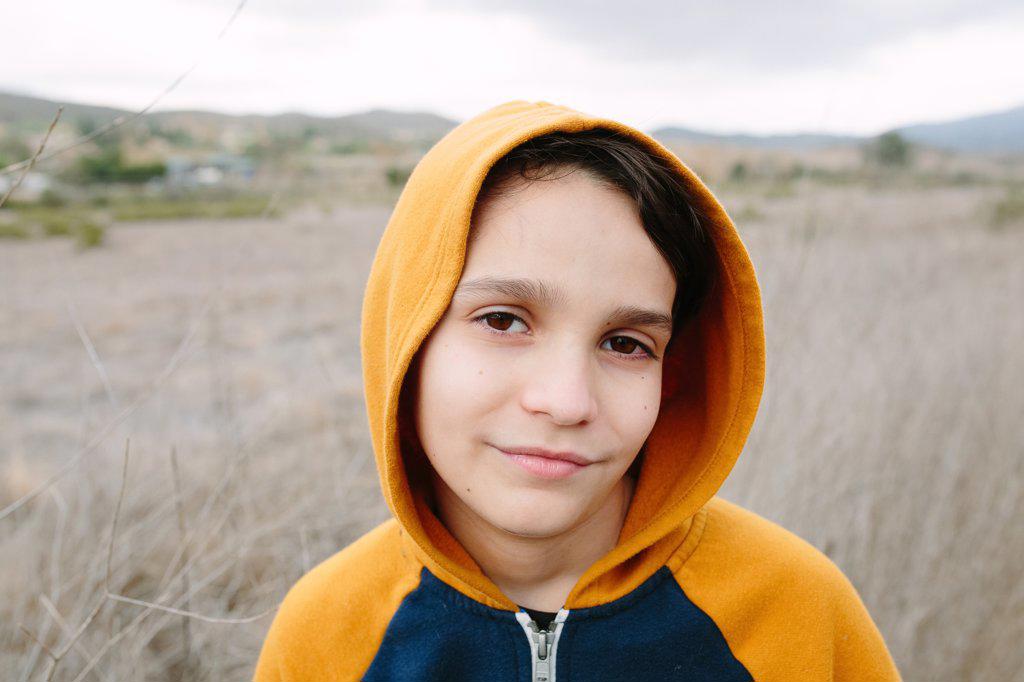 Portrait Of A Boy Wearing An Orange Hoodie Outside In Nature