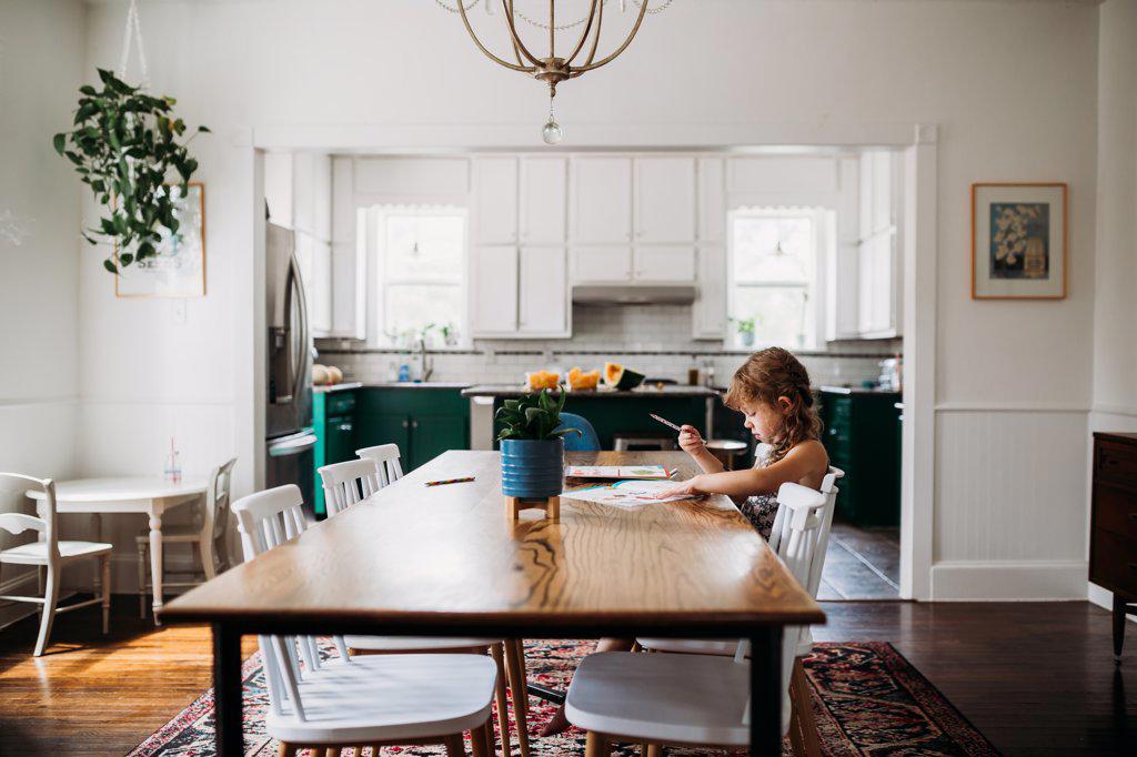 Young girl doing school work at dining room table