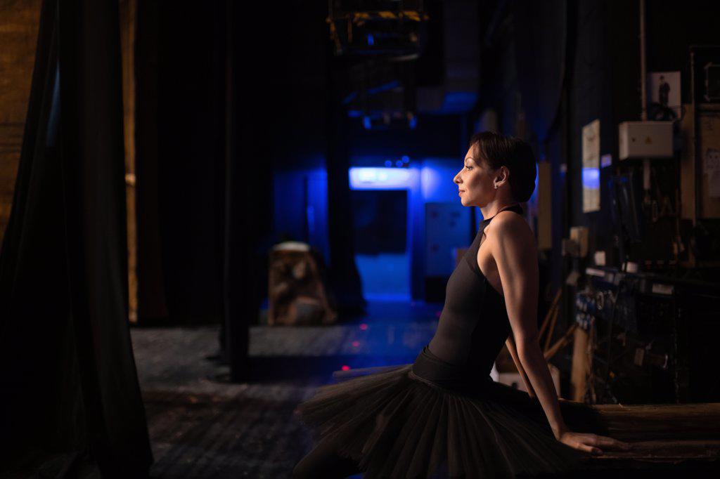 Adult ballerina sitting behind stage