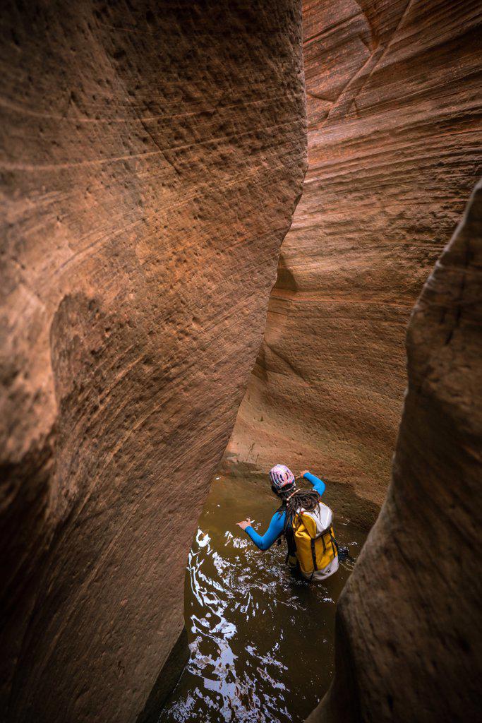 A man wades through deep water to navigate a slot canyon in Zion