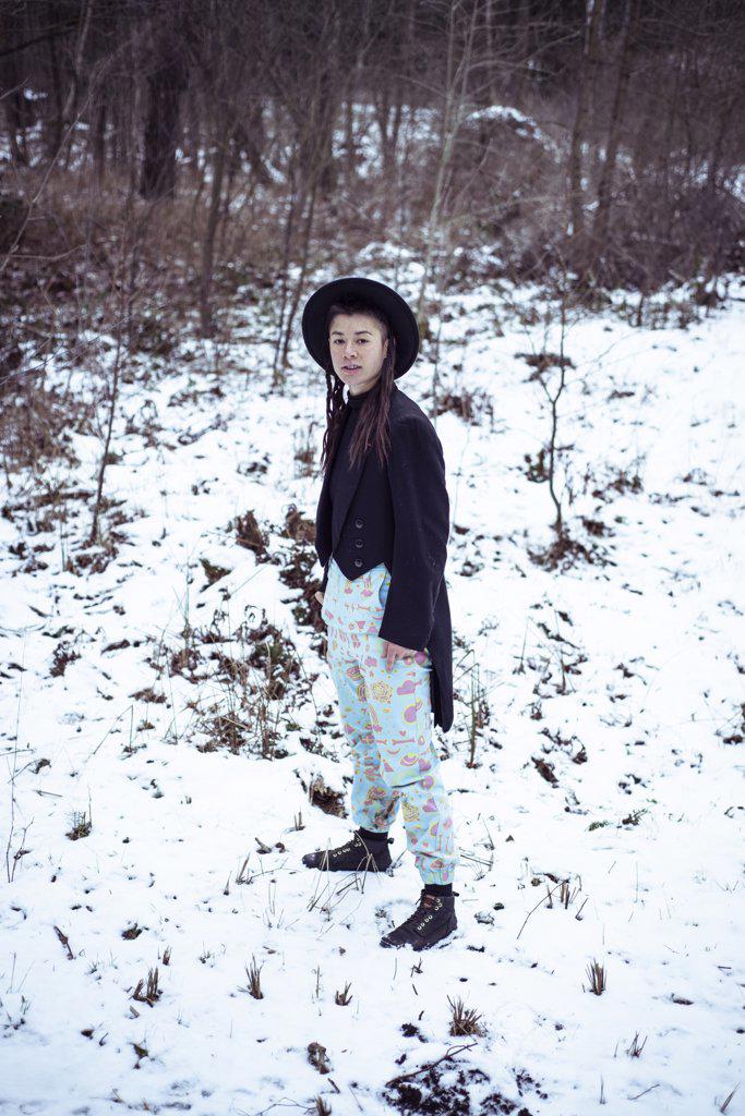 Androgynous mixed-race woman stands with black tuxedo jacket in snow