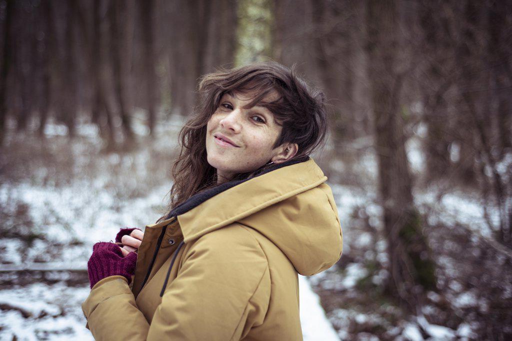 cheerful woman smiles cheekily over shoulder in snowy winter forrest
