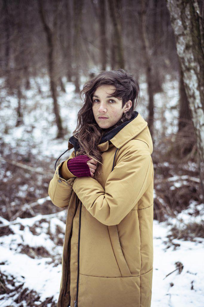 portrait of natural girl with freckles in cold winter snow woods