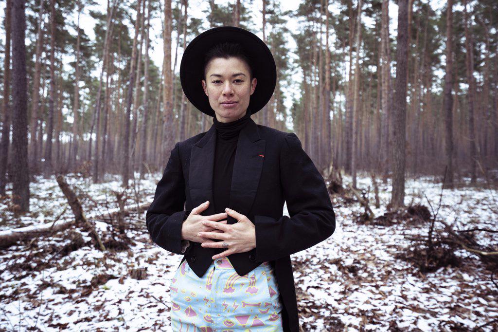 Queer trendy woman stands in white european forrest during winter