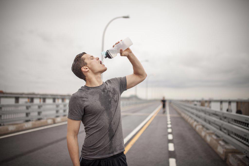 Male athlete pouring water trying to rehydrate during workout