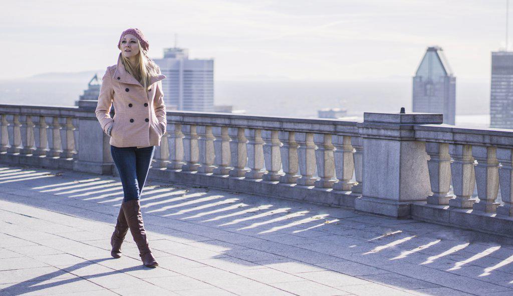 Blonde woman with pink coat and city behind