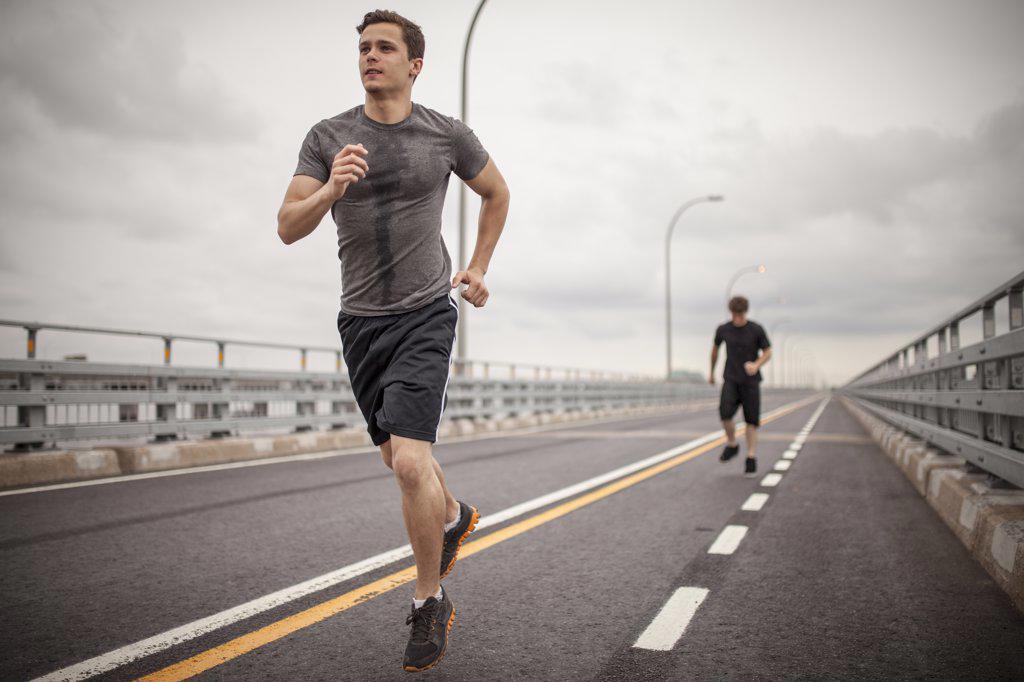 Two male athletes running together on overcast day