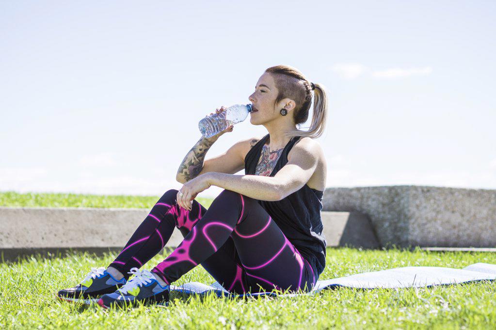 Young female athlete resting and drinking during a water break
