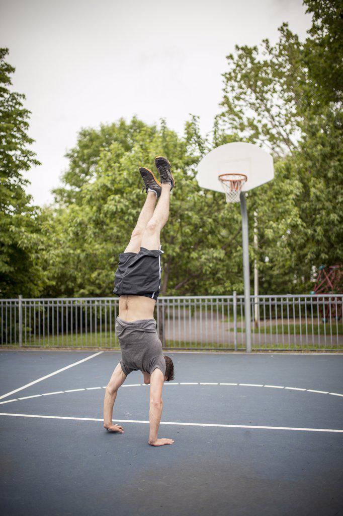 Man doing a handstand on basketball court