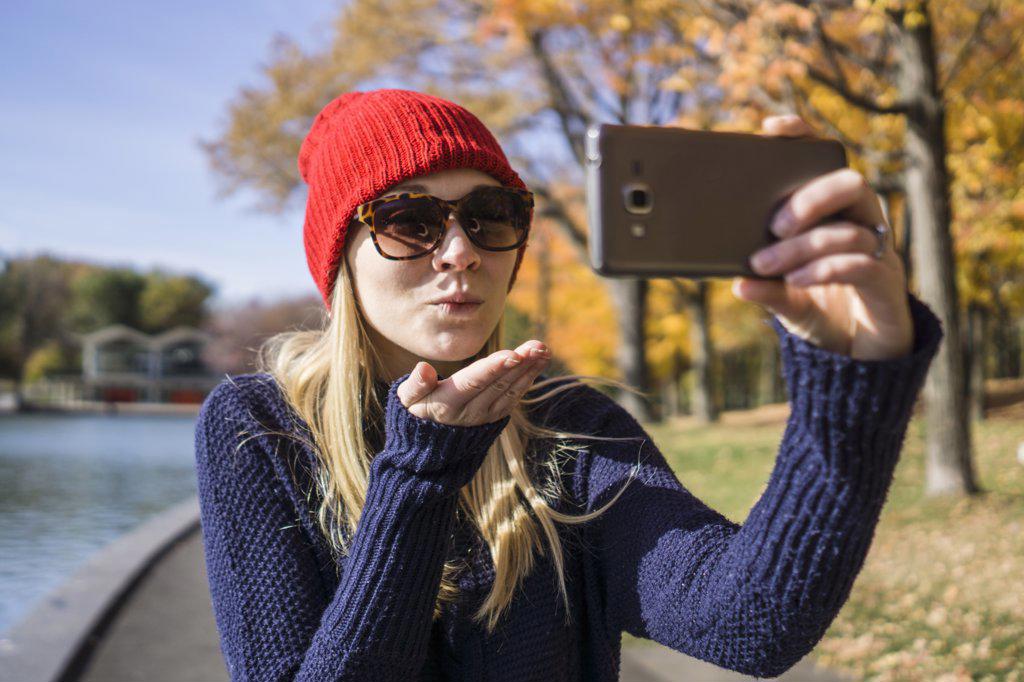 Canadian woman in park using smartphone to take selfie