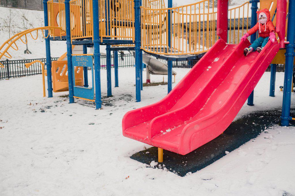 Young child playing on playground in snow