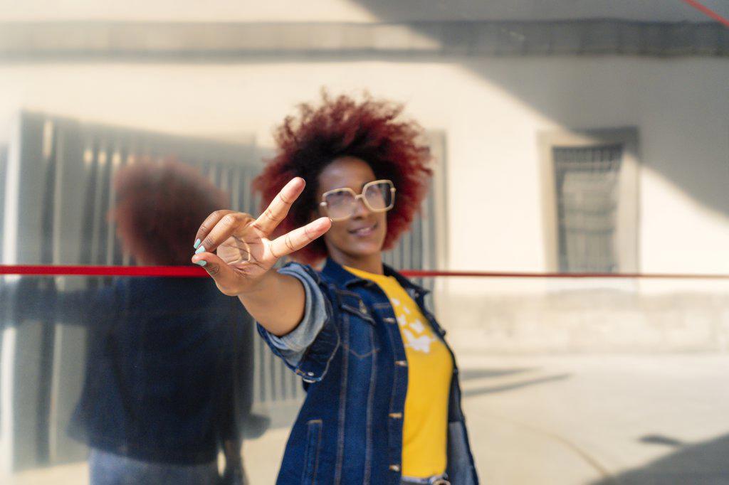 woman with afro hair making victory gesture