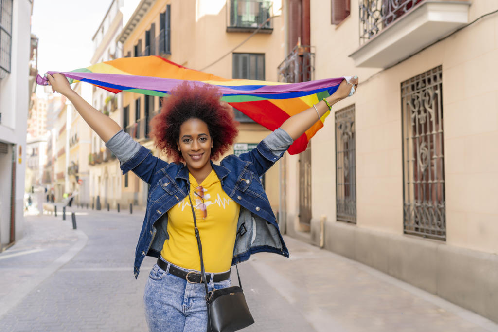 woman with afro hair wearing gay pride flag