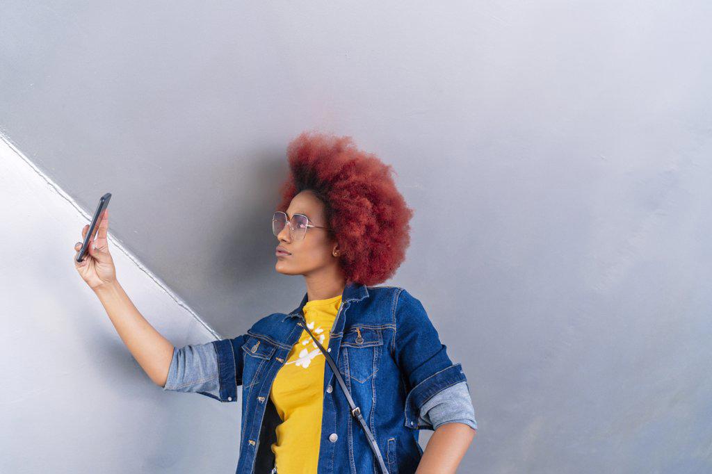 woman with red afro hair taking a picture