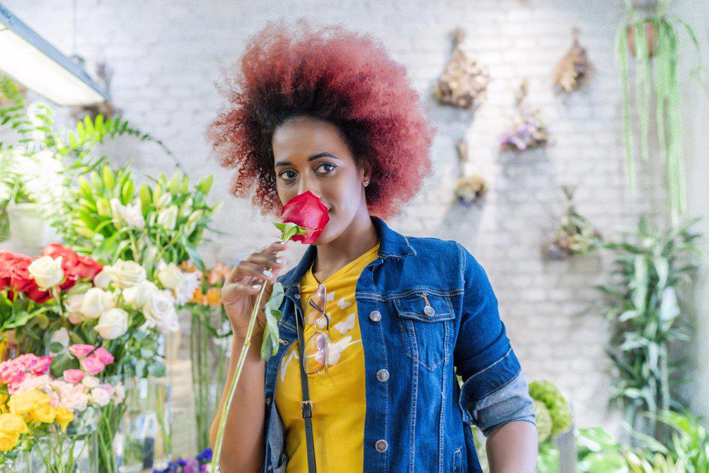 woman with afro hair smelling a pretty rose