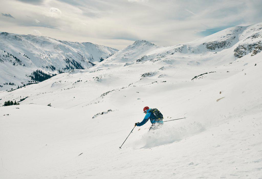 Male skier skis down a powdery slope on a sunny day in Colorado