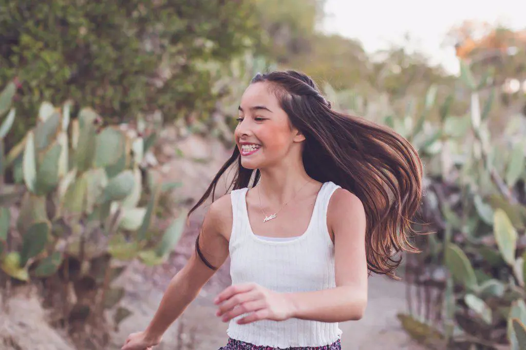 Mixed race girl walking on a cactus trail with her long hair flying.