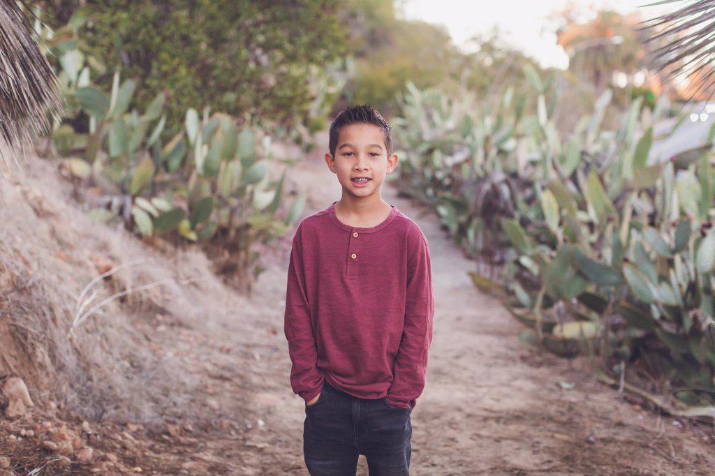 Nine year old boy smiling at the camera, hands in pocket.
