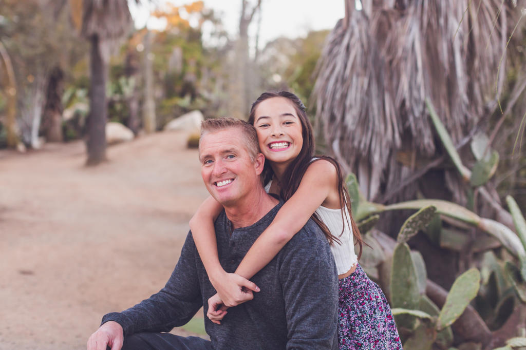 Pre-teen daughter of mixed race hugging her Caucasian father.