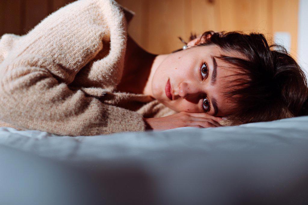 sad woman lying on the bed looking at the camera