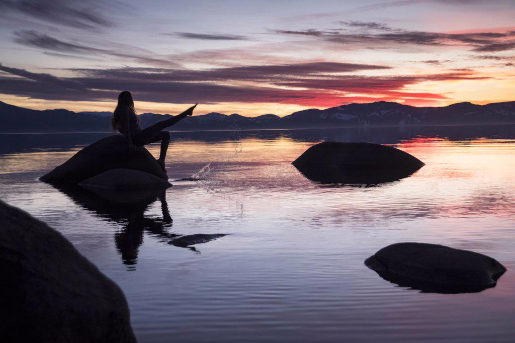 Young adventurous women sitting on rock splashing water Lake Tahoe