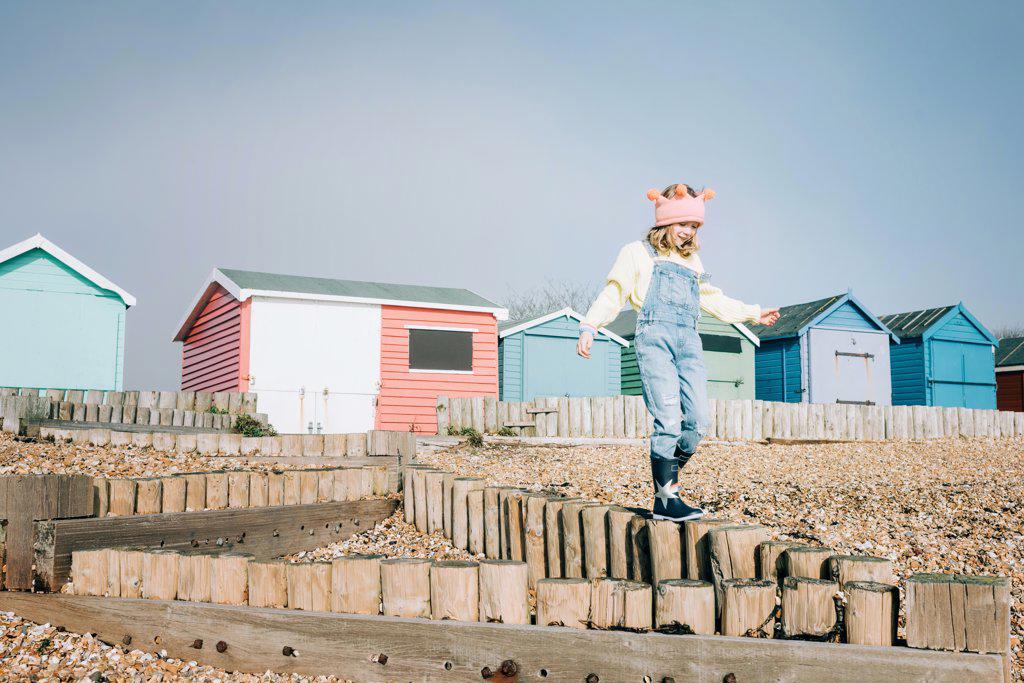 child playfully walking at the beach by colourful beach huts in the UK