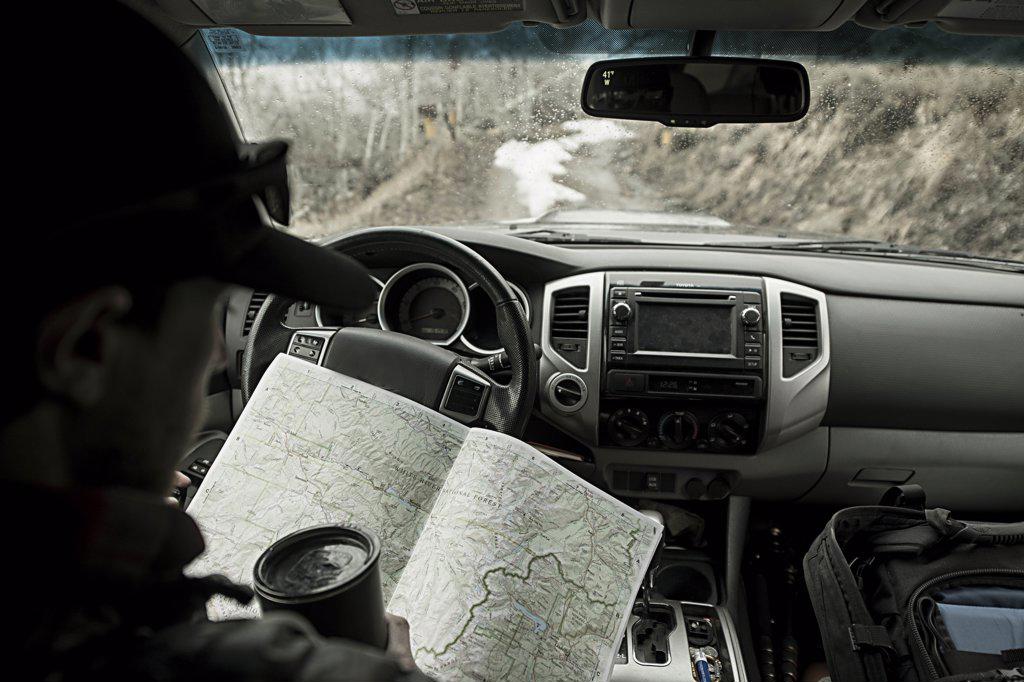 Young male looking at map in truck while driving back roads of Colorad