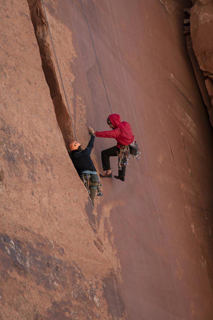 Men high-fiving while climbing cliff at Canyonlands National Park