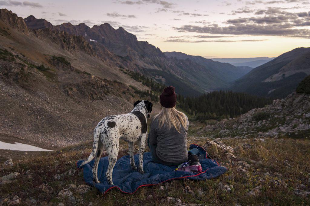 Woman looking at mountains while hiking with dog during sunset