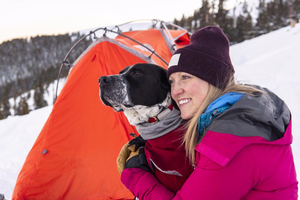 Happy young woman camping with dog during vacation