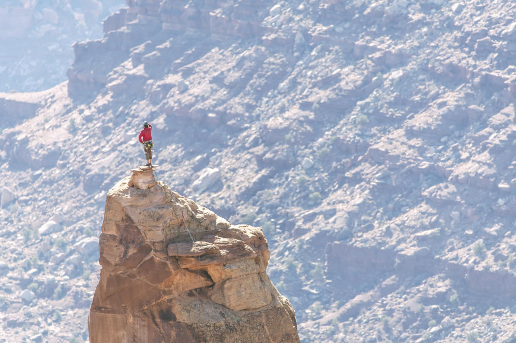 Man on peak of rocky pinnacle at Canyonlands National Park